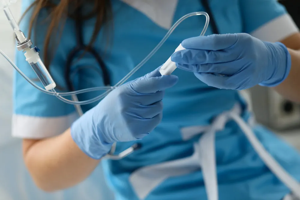 female-nurse-hand-in-blue-protective-gloves-hold-dropper-scaled